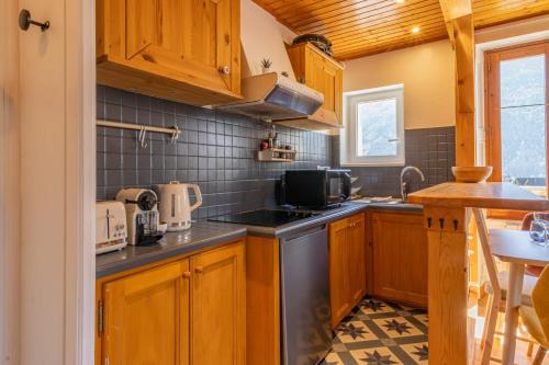 une cuisine avec des armoires en bois et un four à plaques de cuisson dans l'établissement Rimaye Blanche - A bright and cozy 1 bed apartment, à Chamonix-Mont-Blanc