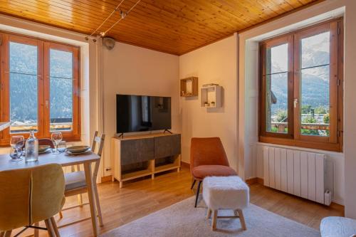 un salon avec une télévision, une table et des chaises dans l'établissement Rimaye Blanche - A bright and cozy 1 bed apartment, à Chamonix-Mont-Blanc