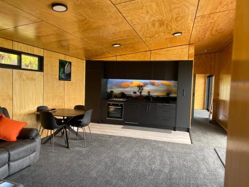 a living room with a couch and a table with a tv at Fenian Retreat in Karamea