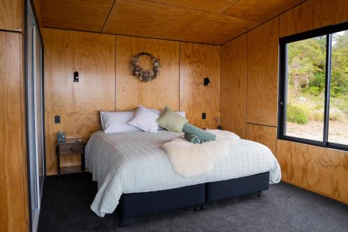 a bedroom with a bed in a room with a window at Fenian Retreat in Karamea