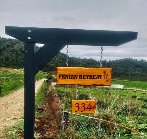 a sign for a farm retreat on the side of a road at Fenian Retreat in Karamea