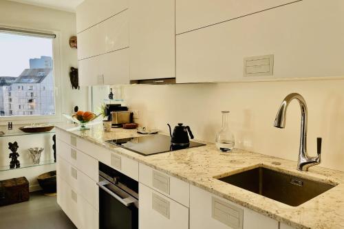 une cuisine avec des armoires blanches et un évier dans l'établissement Apartment for 2 with balcony in Paris, à Paris