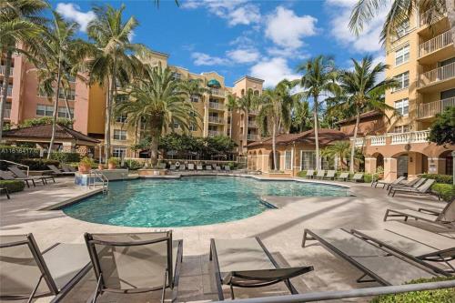 a swimming pool at a resort with chairs and palm trees at The Costal, stunning water view apartment at Aventura Yacht Club, Miami Florida! in Sun Swept Isles