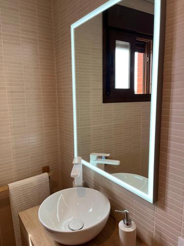 a bathroom with a white sink and a mirror at Duplex con terraza privada y parking a 15 minutos de Sevilla in Dos Hermanas