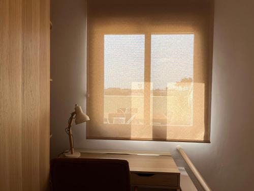 a desk with a lamp in front of a window at Duplex con terraza privada y parking a 15 minutos de Sevilla in Dos Hermanas