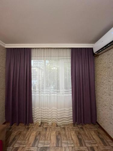 a room with a large window with purple curtains at Apartment at station in Kutaisi