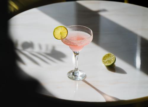 a glass of pink drink with a lime on a table at Santa Lucia Boutique Hotel in Santa Luċija