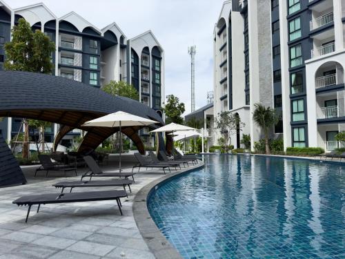 a pool with chairs and umbrellas next to some buildings at The Title Halo 1 Apartment 10 min to Nai Yang Beach in Nai Yang Beach