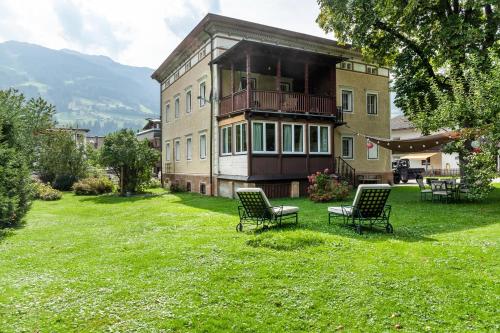 a building with two chairs in the grass in front of it at Apartment Villa Stumm in Stumm