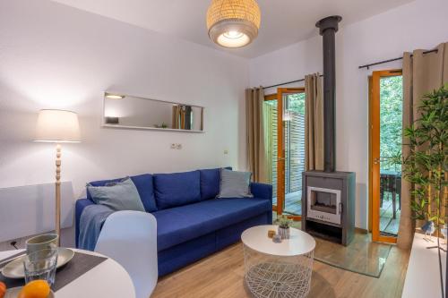 a living room with a blue couch and a stove at Le Sureau Noir S24A - Le Val Joly in Eppe-Sauvage