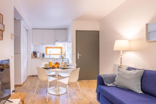 a living room with a table and a blue couch at Le Sureau Noir S24A - Le Val Joly in Eppe-Sauvage