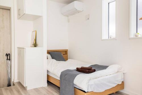 1 dormitorio con 1 cama con paredes y ventanas blancas en 新井1丁目, en Tokio