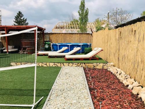 a backyard with two lawn chairs and a fence at Dézsa Apartman Balatonalmádi in Balatonalmádi