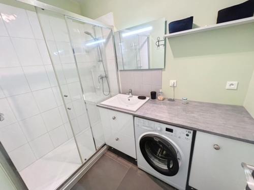 une salle de bain blanche avec une machine à laver et un lavabo dans l'établissement Jadis, l'école de Maisy, port et plage au bout de l'avenue, à Grandcamp-Maisy