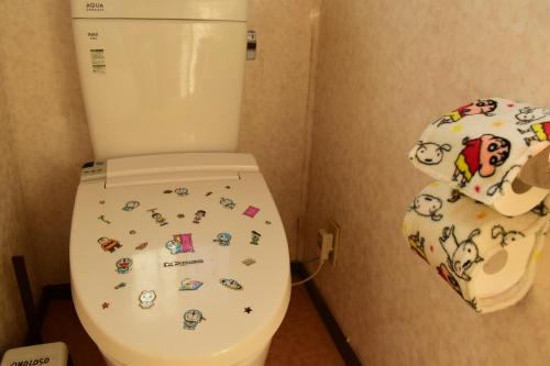 a bathroom with a toilet with stickers on it at OMOLOSO Hostel　オモロソウ ホステル in Beppu