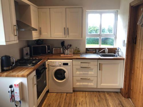 a kitchen with white cabinets and a washing machine at Daisys Rest in Redcross