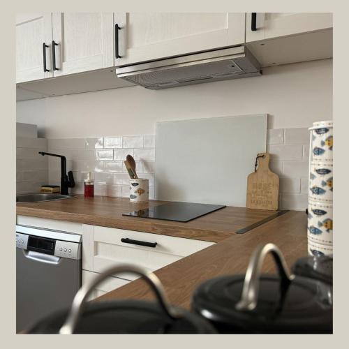 une cuisine avec des armoires blanches et un comptoir en bois dans l'établissement L'appart, à Bandol