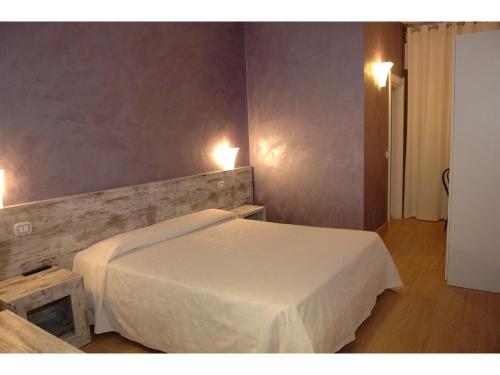 a bedroom with a bed and two lights on the wall at Hotel La Rosa dei Venti in Monte San Giusto