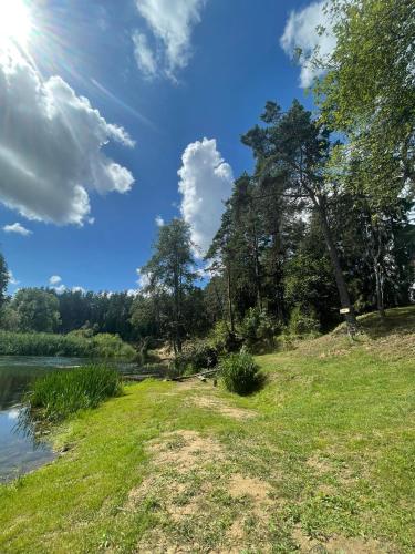 a grassy field next to a river with the sun in the sky at Homestead of Happiness in Zalioji