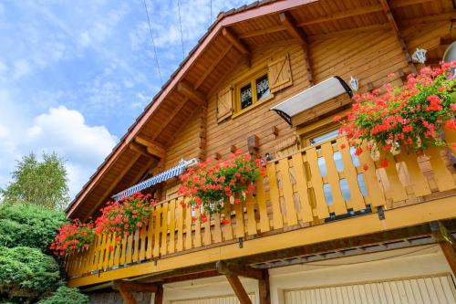 a wooden house with flowers on a balcony at Notre chalet in Vecoux