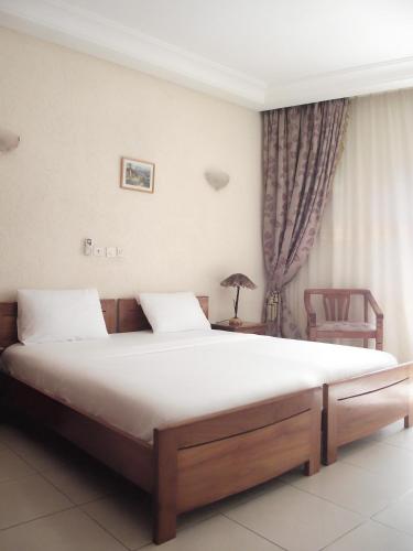 a bedroom with a large bed and a chair at Hotel Ghis Palace in Baguida