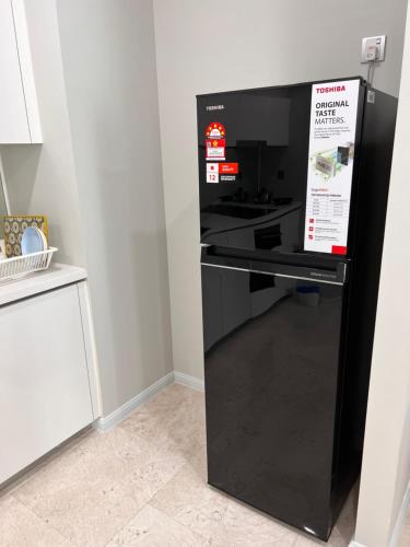 a black refrigerator with a sign on it in a kitchen at Sky Suites at KLCC by Mitstay in Kuala Lumpur