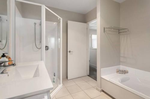 a white bathroom with a shower and a sink at Handy Riccarton Hagley Park CBD 10 Mins in Addington