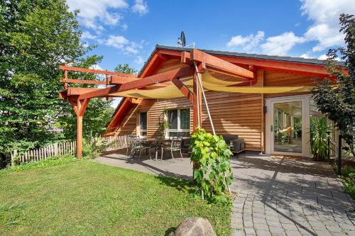 a wooden house with a pergola next to a yard at Leben am Weinberg in Herbstein