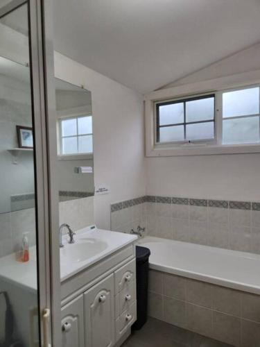a bathroom with a sink and a tub and a mirror at Beautiful vineyard stay in Howrah