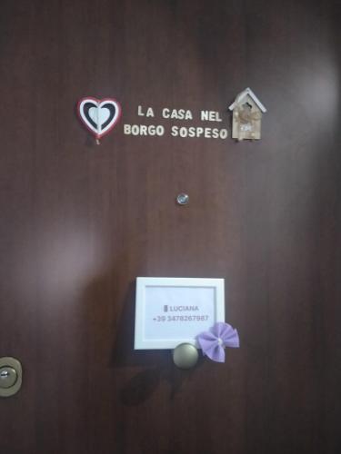 a door with a sign on it with a heart and a ribbon at La casa nel Borgo Sospeso "con vasca e vista panoramica" in Vitorchiano