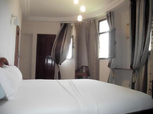 a bedroom with a large white bed and a window at Hotel Ghis Palace in Baguida