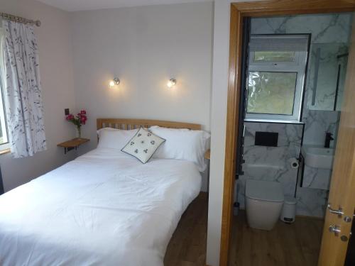 a bedroom with a white bed and a sink at Briardene Cottage - Devon countryside - sleeps 6 in Exeter