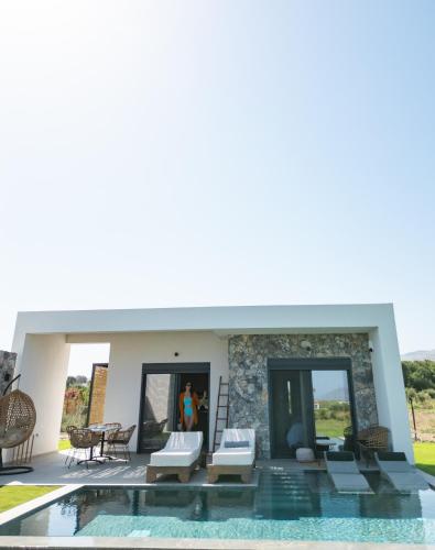 a woman standing in front of a house with a swimming pool at Aphrodite Luxury Suites with private heated pools in Kos Town
