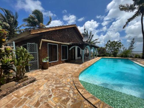 a villa with a swimming pool in front of a house at Villa Fiona in Marumbi