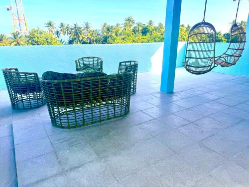 a patio with chairs and swings next to a pool at Sands Grand in Dhigurah