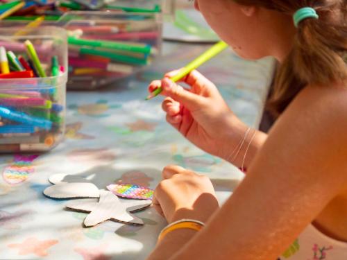 a young girl is making a star craft on a table at Residence with pool and private beach in Talamone just 500 mt from the sea in Talamone