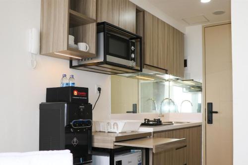 a kitchen with a black refrigerator and a microwave at Homey Designed and Tidy Studio Tokyo Riverside PIK 2 Apartment By Travelio in Rawalembang