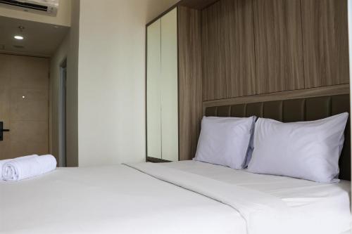 a bed with white sheets and pillows in a room at Homey Designed and Tidy Studio Tokyo Riverside PIK 2 Apartment By Travelio in Rawalembang