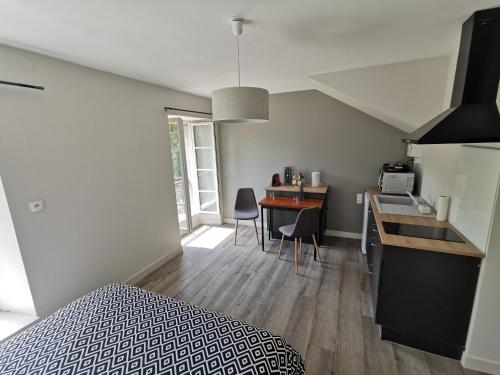 a bedroom with a bed and a kitchen with a table at Moulin Pont Vieux Chambres d'hôtes in Mortagne-sur-Sèvre