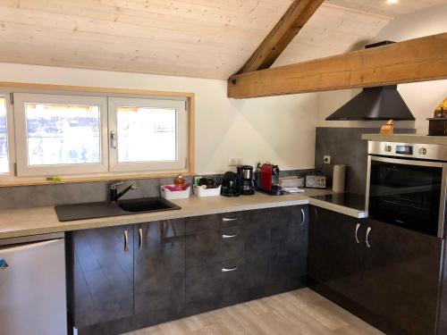 d'une cuisine avec des placards noirs, une cuisinière et des fenêtres. dans l'établissement L'Atelier, à Salins-les-Bains