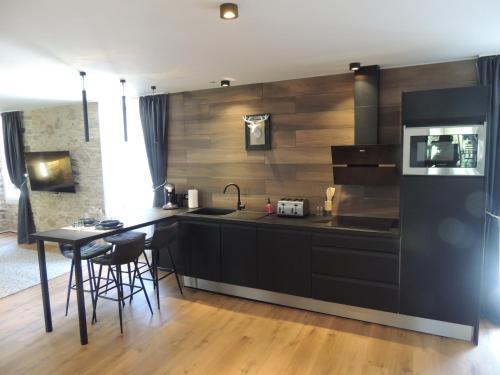 une cuisine avec un comptoir noir et une table dans l'établissement loft dans moulin à eaux du 18éme, à Saint-Dolay