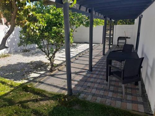 a patio with a table and chairs under a pergola at Weskus Wonderlus - Velddrif in Velddrif