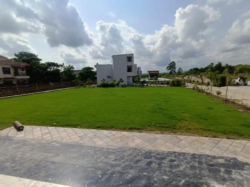 a large grassy field in front of a building at Corbett Tusker Meadows by White Flower in Rāmnagar