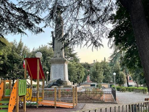 a monument in a park with a fence and a tree at The Selice Loft in Monte San Savino