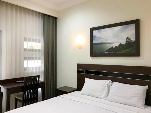 a bedroom with a bed and a desk and a window at Selorejo Resort Mitra RedDoorz in Sekar
