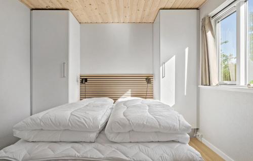 a bedroom with a large white bed with a wooden ceiling at Gorgeous Home In Væggerløse With Sauna in Marielyst