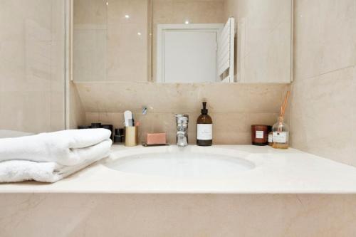 La salle de bains est pourvue d'un lavabo blanc et d'un miroir. dans l'établissement Appartement de luxe 1 chambre Tour Eiffel avec balcon, à Paris