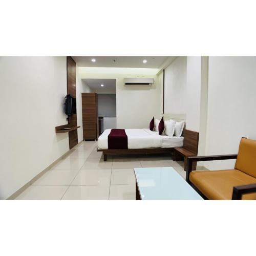 a bedroom with a bed and a couch and a chair at Hotel Ashray Inn Express in Ahmedabad