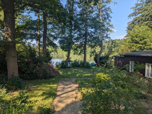 ein Weg, der zu einem Hof mit Bäumen und einem See führt in der Unterkunft Seeidyll in Heidesee