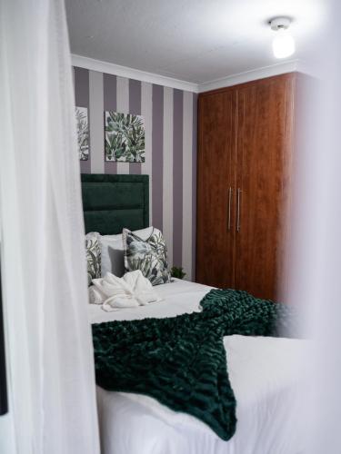 a bedroom with a bed with a green blanket at Plein On Suid Guesthouse in Polokwane